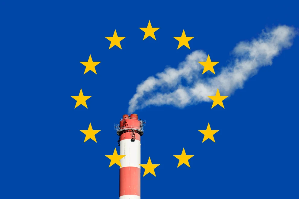 En rökpelare stiger upp ur en skorsten framför den europeiska flaggan.