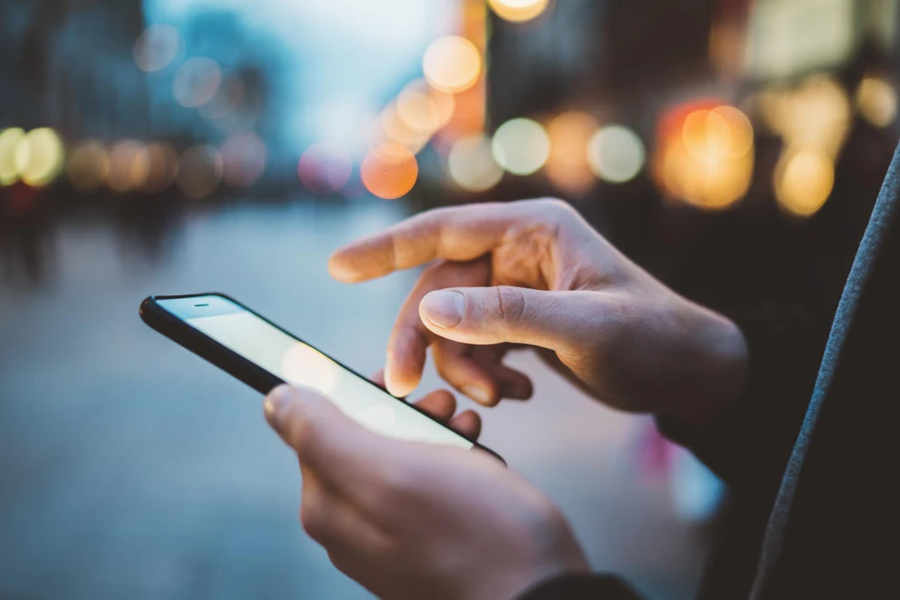 Hand som pekar på mobiltelefon