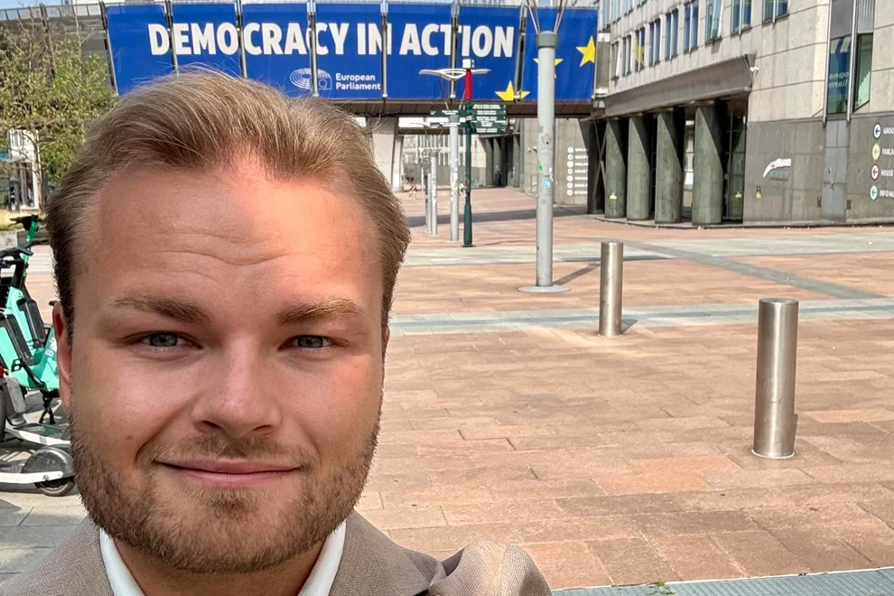 En man som står framför en skylt med texten ”Demokrati i praktiken”.